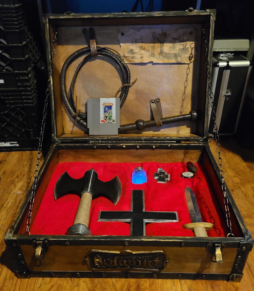 An assortment of medieval weapons and holy artifacts in a wooden box.