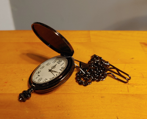 A pocket watch made out of dark gray metal.