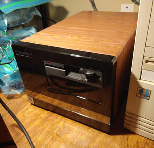 A squat, deep, black computer with a 5 1/4 inch floppy drive and a silver MSDOS badge