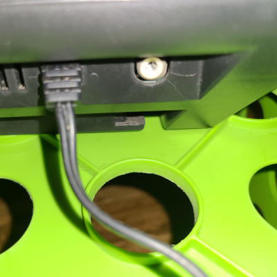 A close up of a black appliance. There is connector on the right and a cable with a strain-relief-gland on the left.