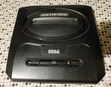Sega Genesis Model 2 - A rounded black square with an oval mound in the center, and two lozenge shaped buttons on the top towards the front.
