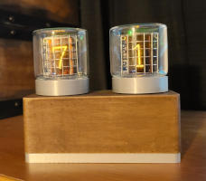 Two glass tubes sit on a wood box. The numbers '7' and '1' glow orange from behind metal grids inside the tubes.