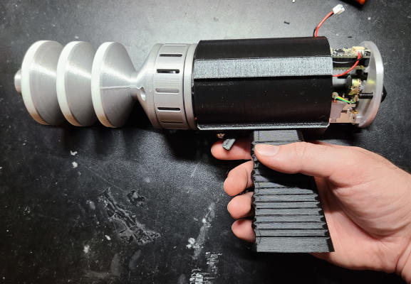 The whole raygun from above. Here it has a black body with no text, and the back panel is loose with exposed electronics and bolt ends.