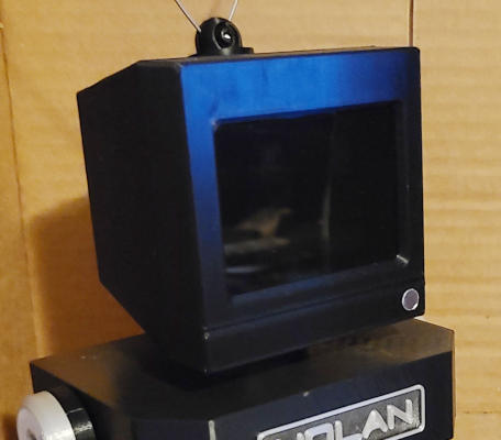 A close up of the head. The TV appears to be switched off: the shiny screen shows only black and reflections.