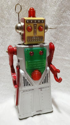 A robot with a silver, skirted, body; a boxy gold head; red arms with claws; a grill for mouth; domed red eyes; antenna for ears, pointing in two different directions; and red dome light on top of its head.