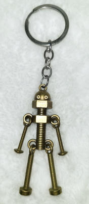 A brass-colored robot with an acorn nut for a head, on a threaded rod body. A hex nut forms shoulders. Attached through loops are smaller bolts that form arms and legs.