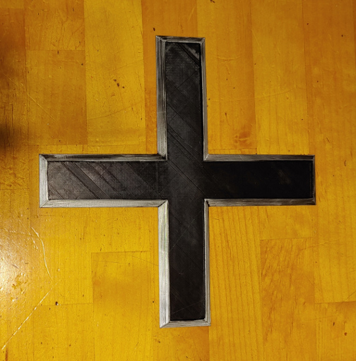 A square black cross with beveled silver edges.