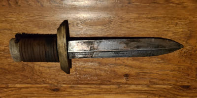 A dirty silver dagger with a gold guard and wooden handle wrapped in leather.